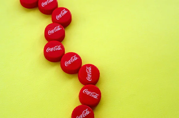 Muchas tapas rojas con logo de cola de coca sobre fondo amarillo —  Fotos de Stock