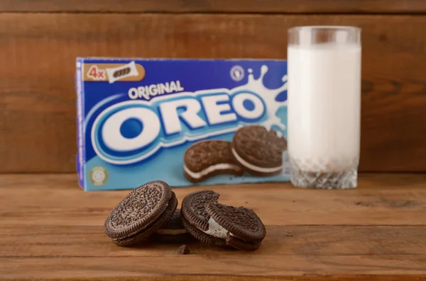 Många Oreo smörgås grädde kex med förpackning och mjölkglas på trä bakgrund — Stockfoto