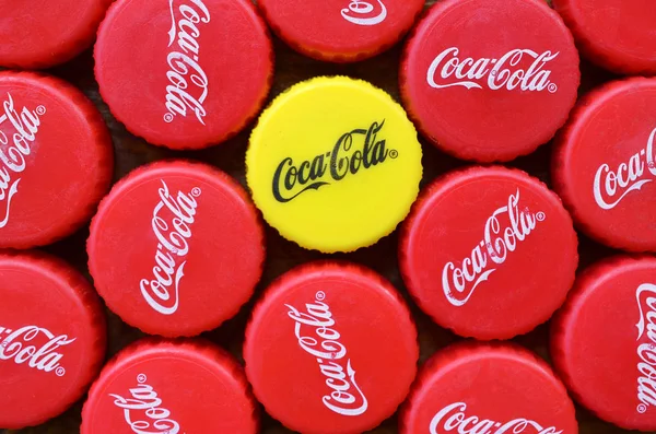 Muitas tampas vermelhas e uma tampa de plástico amarelo com logotipo de coca cola fechar — Fotografia de Stock