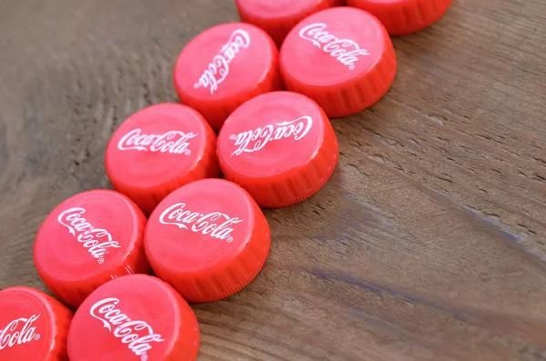 Many red caps with coca cola logo on wooden background — Stock Photo, Image