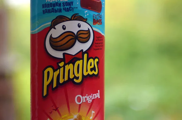 Fechar vermelho Pringles Snacks pacote cilindro em árvores verdes fundo — Fotografia de Stock