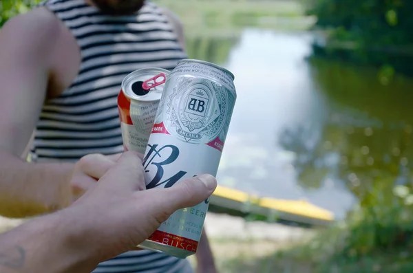 Junger Mann züchtet mit Freund Budweiser Knospenbierdose auf verschwommenem Fluss mit Kajak und Bäumen — Stockfoto