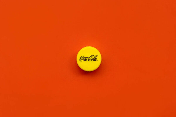 Крышка бутылки с логотипом Coca Cola на красном фоне

