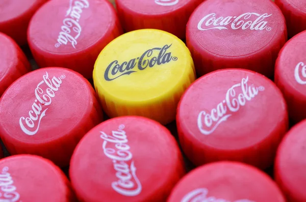 Banyak penutup merah dan satu tutup plastik kuning dengan logo cola coca menutup — Stok Foto