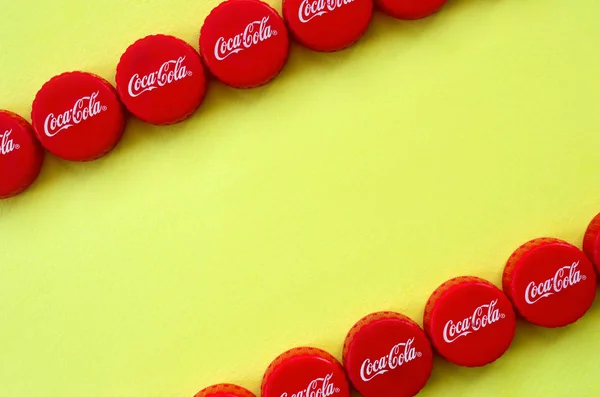 Muchas tapas rojas con logo de cola de coca sobre fondo amarillo —  Fotos de Stock