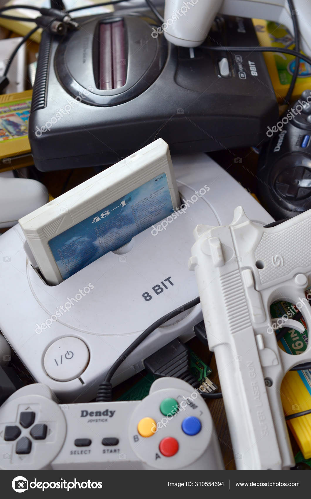 Pile of old 8 bit video game consoles and many gaming accessories