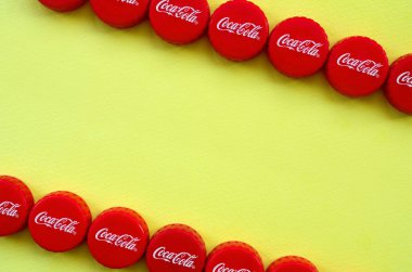Sarı zemin üzerinde Coca Cola logosu olan bir sürü kırmızı başlık