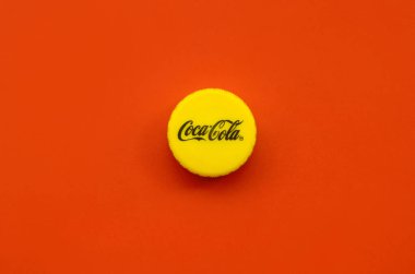 Kırmızı zemin üzerinde Coca Cola logosu olan tek sarı şişe kapağı.