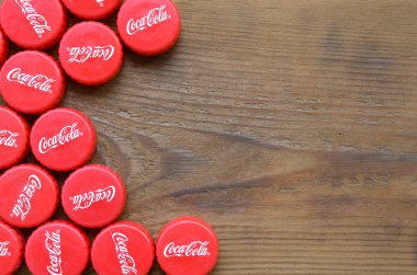 Ahşap zemin üzerinde Coca Cola logosu olan bir sürü kırmızı şapka.