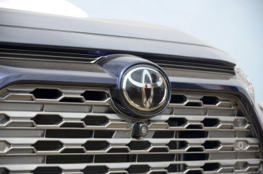 Gümüş renkli arabada Toyota logosu. Ön taraf açık havada.