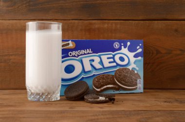 Bir sürü Oreo sandviçi kremalı bisküvi ve tahta arka planda süt bardağı.