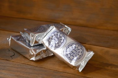 Oreo sandviç kremalı bisküviler siyah ahşap arka planda mini paketler.