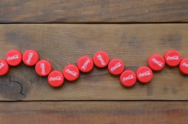 Ahşap zemin üzerinde Coca Cola logosu olan bir sürü kırmızı şapka.