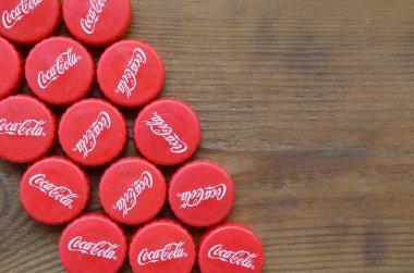 Ahşap zemin üzerinde Coca Cola logosu olan bir sürü kırmızı şapka.