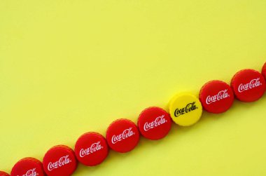 Sarı zemin üzerinde Coca Cola logosu olan bir sürü kırmızı başlık