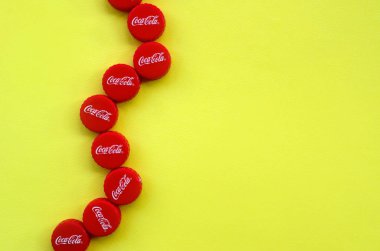 Sarı zemin üzerinde Coca Cola logosu olan bir sürü kırmızı başlık