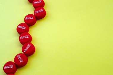 Sarı zemin üzerinde Coca Cola logosu olan bir sürü kırmızı başlık