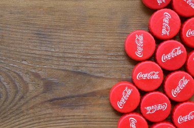 Ahşap zemin üzerinde Coca Cola logosu olan bir sürü kırmızı şapka.