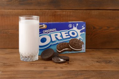 Bir sürü Oreo sandviçi kremalı bisküvi ve tahta arka planda süt bardağı.