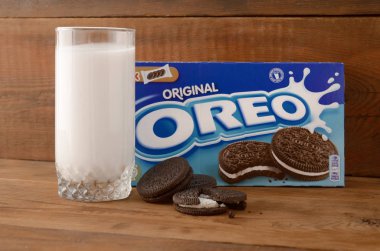 Bir sürü Oreo sandviçi kremalı bisküvi ve tahta arka planda süt bardağı.