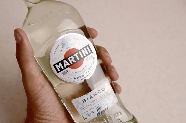 Pullo Vermouth Martini Rossi mies kädessä beige seinään tausta — kuvapankkivalokuva