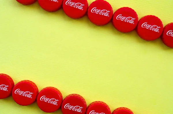 Muchas tapas rojas con logo de cola de coca sobre fondo amarillo —  Fotos de Stock