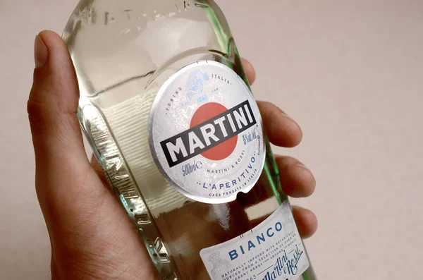 Pullo Vermouth Martini Rossi mies kädessä beige seinään tausta — kuvapankkivalokuva