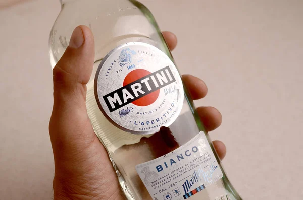 Pullo Vermouth Martini Rossi mies kädessä beige seinään tausta — kuvapankkivalokuva