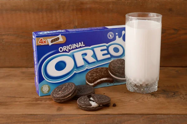 De nombreux biscuits à la crème sandwich OREO avec emballage et verre de lait sur fond en bois — Photo