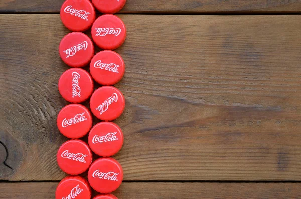 Veel rode caps met coca cola logo op houten ondergrond — Stockfoto