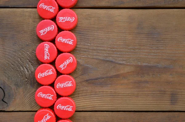 Banyak topi merah dengan logo coca cola pada latar belakang kayu — Stok Foto