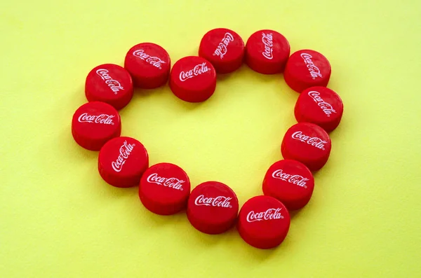 Heart of many red caps with coca cola logo on yellow background — Stok Foto
