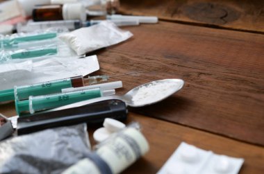 Uyuşturucu hazırlamak için pek çok uyuşturucu madde ve cihaz eski bir ahşap masada yatıyor.