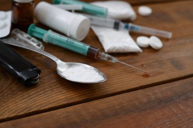 Uyuşturucu hazırlamak için pek çok uyuşturucu madde ve cihaz eski bir ahşap masada yatıyor.