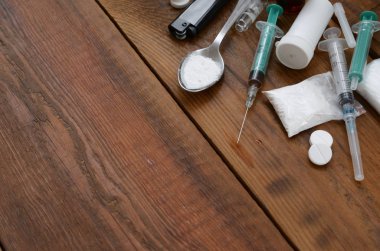 Uyuşturucu hazırlamak için pek çok uyuşturucu madde ve cihaz eski bir ahşap masada yatıyor.