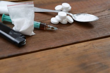 Uyuşturucu hazırlamak için pek çok uyuşturucu madde ve cihaz eski bir ahşap masada yatıyor.