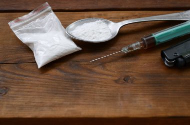 Şırınga çakmağı ve tahta arka planda beyaz toz dolu kaşık. Eroin bağımlılığı konsepti