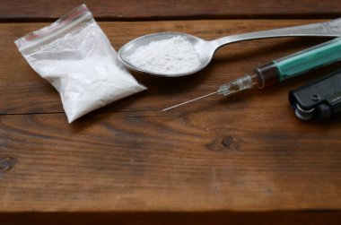 Syringe lighter and spoon full of white powder on wooden background. Heroin drug addiction concept clipart