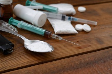 Uyuşturucu hazırlamak için pek çok uyuşturucu madde ve cihaz eski bir ahşap masada yatıyor.