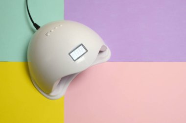 Uv Led tırnak lambası jel yöntemi ile iyileştirme işlemi için Pastel çok renkli tablo üzerinde yatar