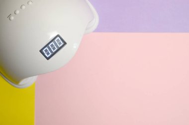 Uv Led tırnak lambası jel yöntemi ile iyileştirme işlemi için Pastel çok renkli tablo üzerinde yatar