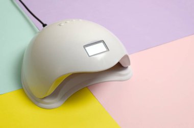 Uv Led tırnak lambası jel yöntemi ile iyileştirme işlemi için Pastel çok renkli tablo üzerinde yatar