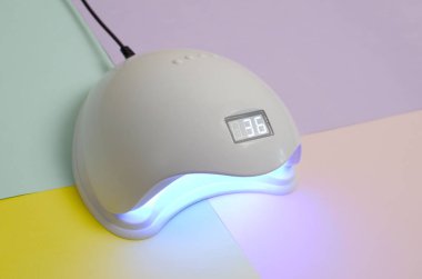 Uv Led tırnak lambası jel yöntemi ile iyileştirme işlemi için Pastel çok renkli tablo üzerinde yatar