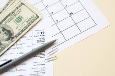 Irs Form W-2g Belli Kumar boş yalanlar ve takvim sayfasında bir sürü yüz dolarlık banknotlar