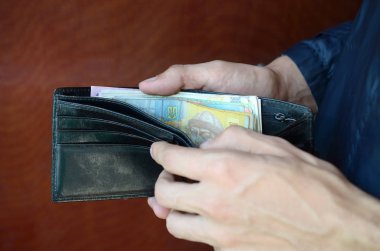 Erkek eli kapalı cüzdanı ya da cüzdanı Ukrayna para birimi Hryvnia ile açmış.