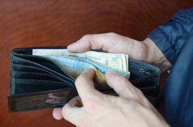 Erkek eli kapalı cüzdanı ya da cüzdanı Ukrayna para birimi Hryvnia ile açmış.