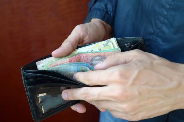 Erkek eli kapalı cüzdanı ya da cüzdanı Ukrayna para birimi Hryvnia ile açmış.