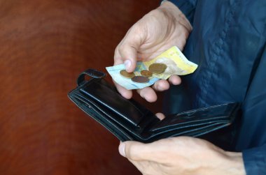 Ukrayna 'nın küçük banknotları ve eski siyah çantalı bozuk paraları olan bir erkek eli.