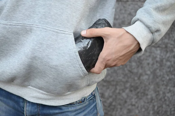 Narcotraficante tomando bolsa con cocaína de bolsillo con capucha sobre fondo de baldosas oscuras de cerca — Foto de Stock