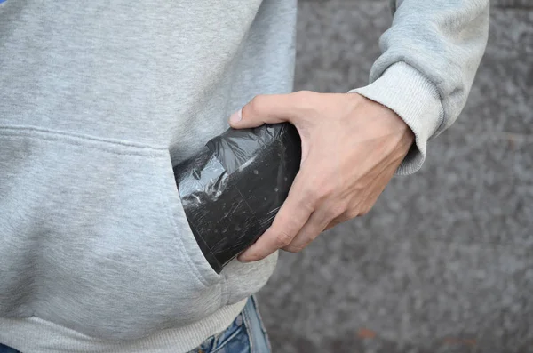 Narcotraficante tomando bolsa con cocaína de bolsillo con capucha sobre fondo de baldosas oscuras de cerca — Foto de Stock